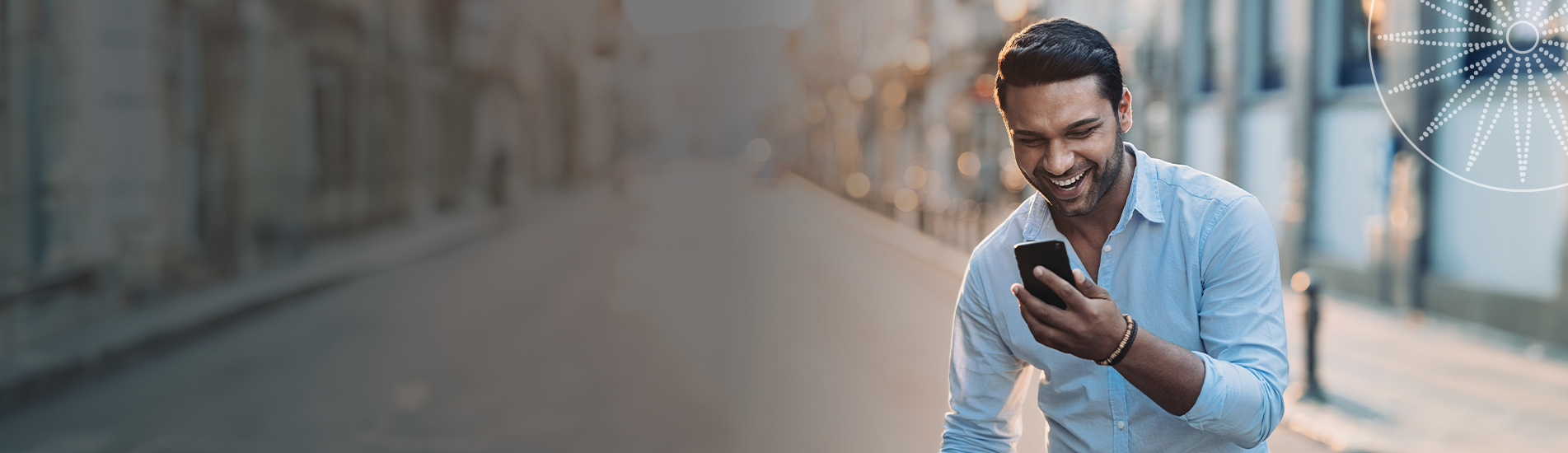 man smiling while staring at his phone screen